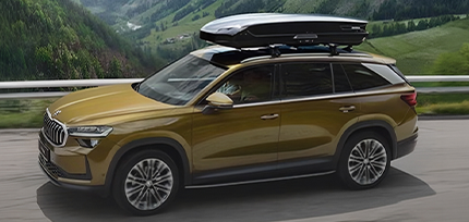 &Scaron;koda SUV mit Dachbox f&auml;hrt durch eine bergige Landschaft.