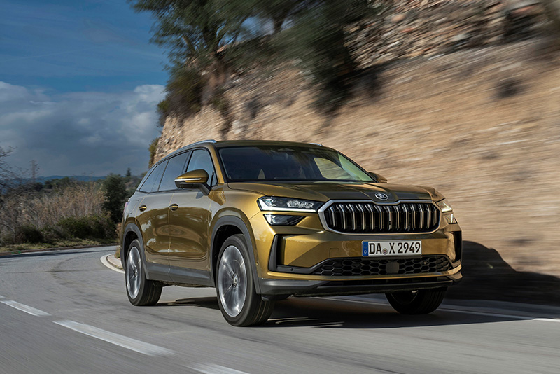 Ein Skoda Kodiaq in der Dreiviertelansicht von vorne beim Fahren auf einer Landstra&szlig;e bei hohem Tempo
