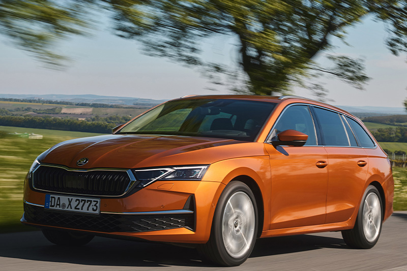 Ein orangener Skoda Octavia Combi in der Dreiviertelansicht von vorne beim Fahren auf einer Landstra&szlig;e mit hohem Tempo
